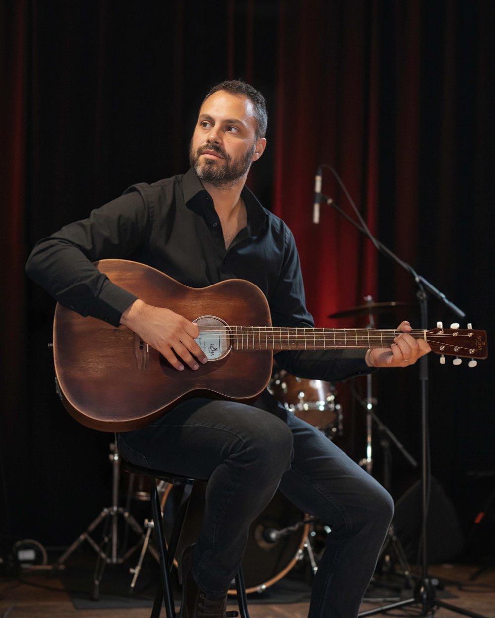 Jean-Christophe Vignon, professeur de guitare, assis sur scène avec une guitare acoustique